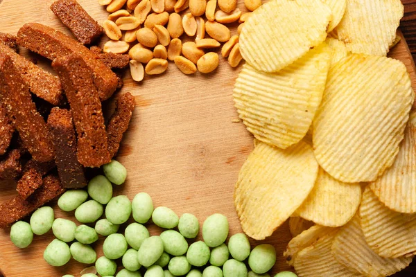 Verschiedene Trockene Snacks Auf Einem Holzbrett Chips Erdnüsse Croutons Wasabi — Stockfoto
