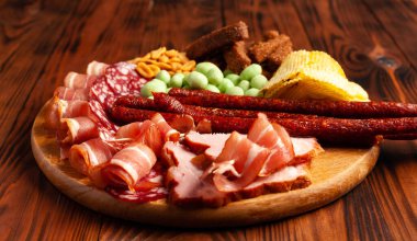 Kopya alanı olan ahşap bir masada çeşitli bira aperatifleri. Sosis, jambon, pastırma. Tuzlu abur cubur, kızarmış ekmek, fıstık, wasabi fındığı..