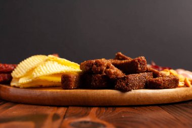 Kopya alanı olan ahşap bir masada çeşitli bira aperatifleri. Sosis, jambon, pastırma. Tuzlu abur cubur, kızarmış ekmek, fıstık, wasabi fındığı..