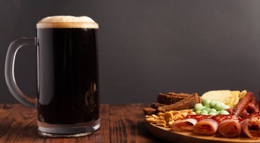Bir kupa bira ve ahşap bir masada çeşitli atıştırmalıklar. Sosis, salam, jambon, pastırma. Bira, tuzlu çerez, cips, wasabi fındığı, tuzlu fıstık, kızarmış ekmek..