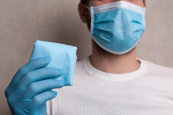 Portrait of a masked man with antiseptic on a napkin. The concept of hygiene during the coronavirus epidemic and remedies.