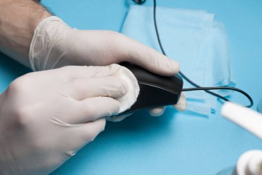 Dezenfeksiyona yakın çekim, beyaz eldivenli bir bilgisayar faresinin temizlenmesi. Koronavirüs enfeksiyonunun önlenmesi.