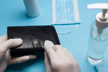 Çantayı beyaz eldivenlerle temizleyen dezenfeksiyona yakın çekim. Koronavirüs enfeksiyonunun önlenmesi.