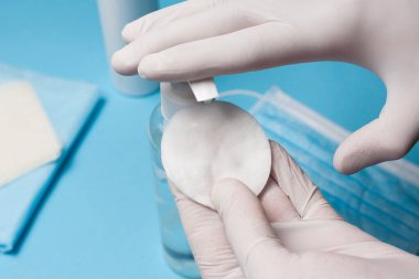 Dezenfeksiyona yakın çekim, beyaz eldivenli pamuk bloknotta antibakteriyel madde kullanımı. Koronavirüs enfeksiyonunun önlenmesi.