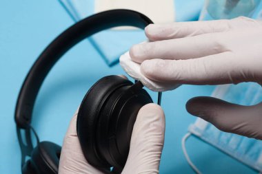 Dezenfeksiyona yakın çekim, kulaklıkları beyaz eldivenlerle temizlemek. Koronavirüs enfeksiyonunun önlenmesi.