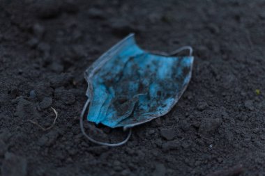 Kıyametten sonra yerde bir tıbbi maske yatıyor. Dünyanın sonu, tehdit koronavirüsü - kavram. Kimse..