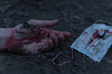 Kanlı bir el uzanıp yerde yatan tıbbi kanlı bir maske. Koronavirüs konsepti ve bu hastalığın neden olduğu kıyamet tüm dünyaya yayıldı. Korkunç..