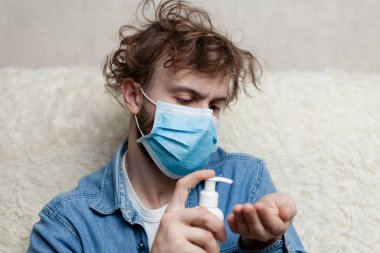 Evde elinde bir şişe antiseptik olan adam. Karantina koronavirüsü ve hijyen ürünleri kavramı. Elinde dezenfektan var..