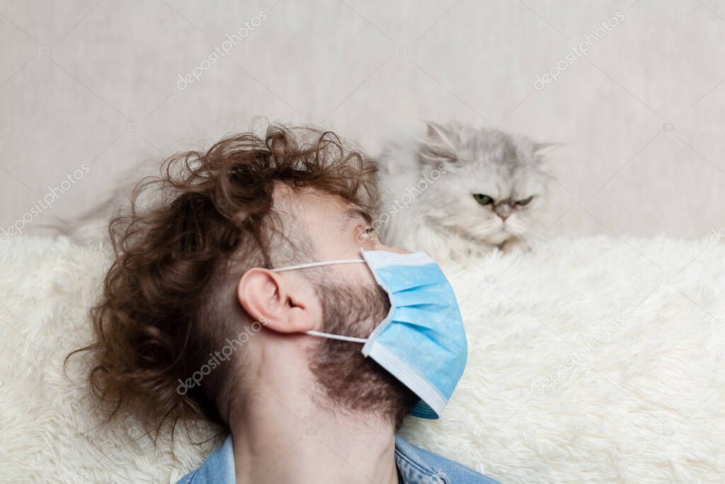 A man with his pet is sitting on a sofa at home. Quarantine coronavirus.