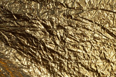 İnce, buruşmuş bir folyonun dokusu. Buruşuk folyo arka plan. Fotokopi kağıdı. Altın krom rengi.