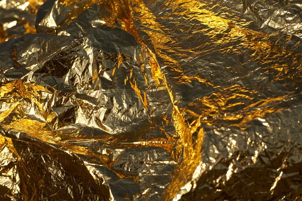 Texture of a thin crumpled sheet of foil. Crumpled foil background. Stock photo foil. Gold chrome color.