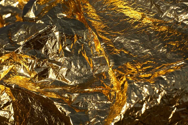 Texture of a thin crumpled sheet of foil. Crumpled foil background. Stock photo foil. Gold chrome color.