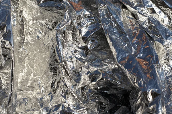 Texture of a thin crumpled sheet of foil. Crumpled foil background. Stock photo foil. Silver chrome color.