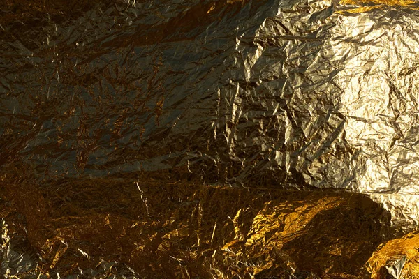 Texture of a thin crumpled sheet of foil. Crumpled foil background. Stock photo foil. Gold chrome color.