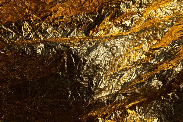Texture of a thin crumpled sheet of foil. Crumpled foil background. Stock photo foil. Gold chrome color.