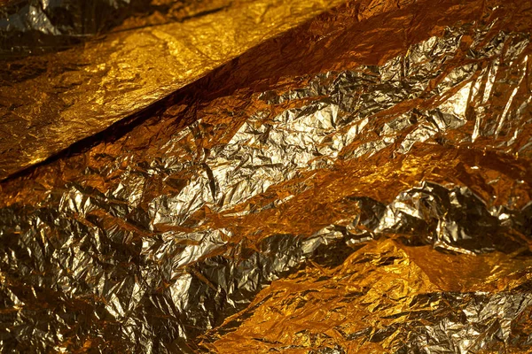 Texture of a thin crumpled sheet of foil. Crumpled foil background. Stock photo foil. Gold chrome color.