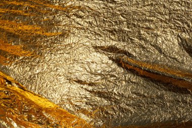 İnce, buruşmuş bir folyonun dokusu. Buruşuk folyo arka plan. Fotokopi kağıdı. Altın krom rengi.