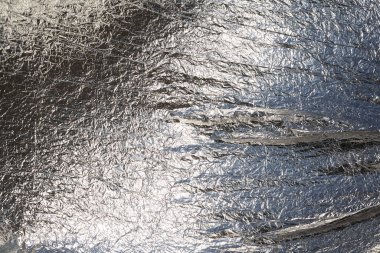 İnce, buruşmuş bir folyonun dokusu. Buruşuk folyo arka plan. Fotokopi kağıdı. Gümüş krom rengi.