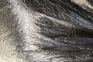 İnce, buruşmuş bir folyonun dokusu. Buruşuk folyo arka plan. Fotokopi kağıdı. Gümüş krom rengi.