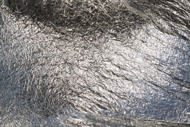 İnce, buruşmuş bir folyonun dokusu. Buruşuk folyo arka plan. Fotokopi kağıdı. Gümüş krom rengi.