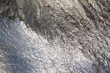 İnce, buruşmuş bir folyonun dokusu. Buruşuk folyo arka plan. Fotokopi kağıdı. Gümüş krom rengi.