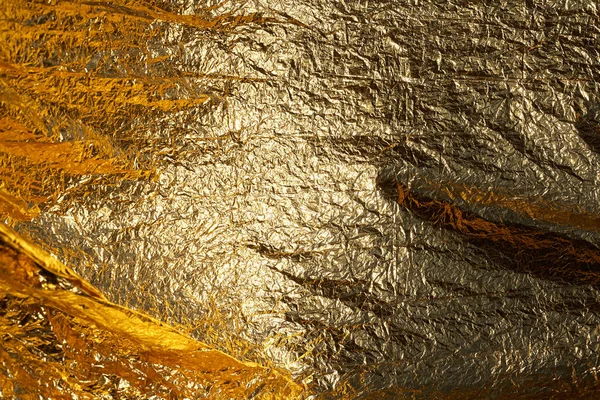 Texture of a thin crumpled sheet of foil. Crumpled foil background. Stock photo foil. Gold chrome color.