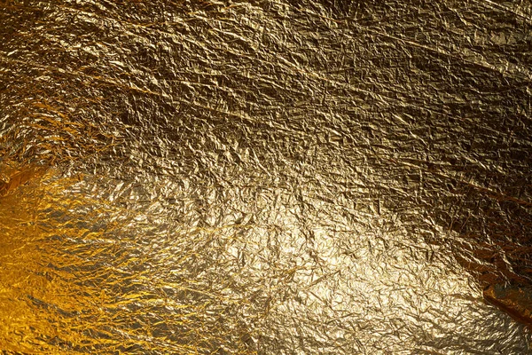 Texture of a thin crumpled sheet of foil. Crumpled foil background. Stock photo foil. Gold chrome color.