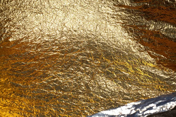 Texture of a thin crumpled sheet of foil. Crumpled foil background. Stock photo foil. Gold chrome color.