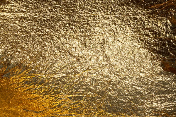 Texture of a thin crumpled sheet of foil. Crumpled foil background. Stock photo foil. Gold chrome color.