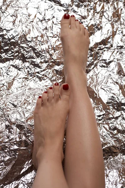 箔の形で美しい背景に美しい女性の足 女性の足のファッショナブルな写真 赤いペディキュア — ストック写真