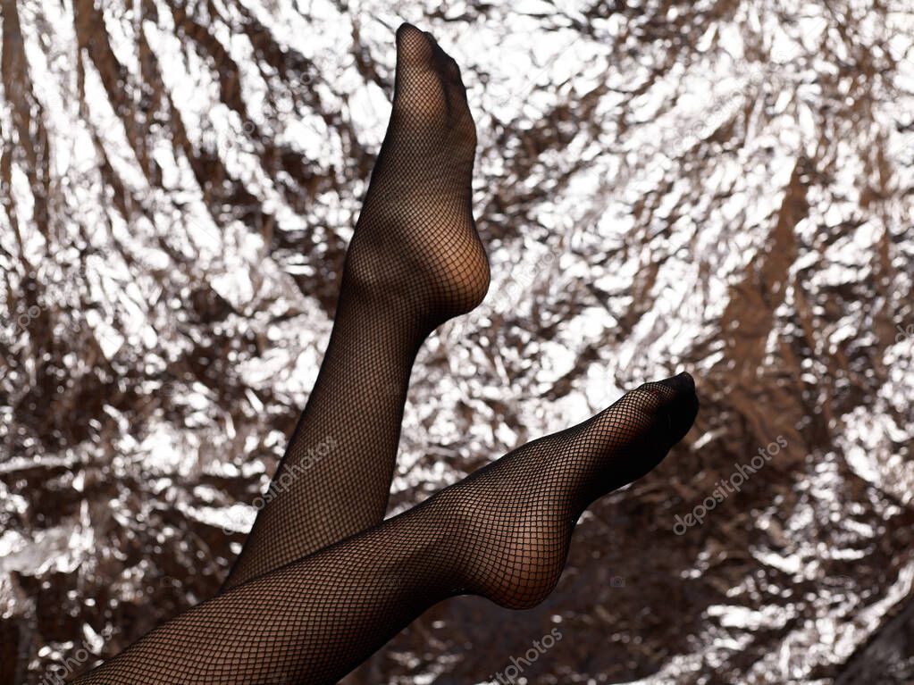 Beautiful female legs in mesh tights. Stock-fashionable black mesh tights and sexy feets of a young girl.