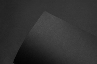 Siyah masadaki boş siyah defter, sahte fotoğraf. Tasarım için kopyalama alanı olan boş siyah kapak şablonu. Siyah üzerine siyah, minimal tasarım konsepti.