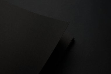 Siyah masadaki boş siyah defter, sahte fotoğraf. Tasarım için kopyalama alanı olan boş siyah kapak şablonu. Siyah üzerine siyah, minimal tasarım konsepti.