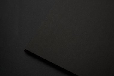 Siyah masadaki boş siyah defter, sahte fotoğraf. Tasarım için kopyalama alanı olan boş siyah kapak şablonu. Siyah üzerine siyah, minimal tasarım konsepti.