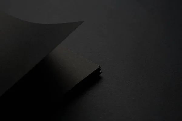 Blank black notebook on a black table, mockup photo. Blank black cover template with copy space for design. Black on black, minimal design concept.
