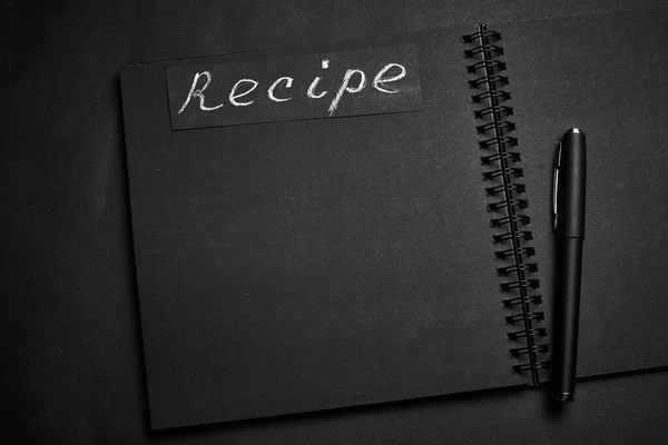 Black notebook on a black table. Notebook for recipes with blank for text.