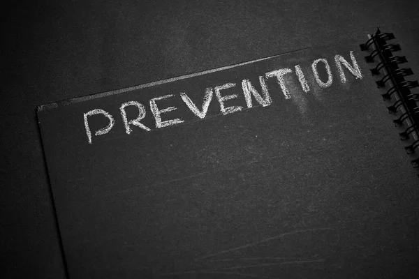 Prevention word written on a notepad with blank space. Blank black notepad background.