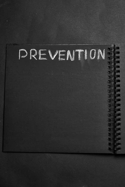 Prevention word written on a notepad with blank space. Blank black notepad background.