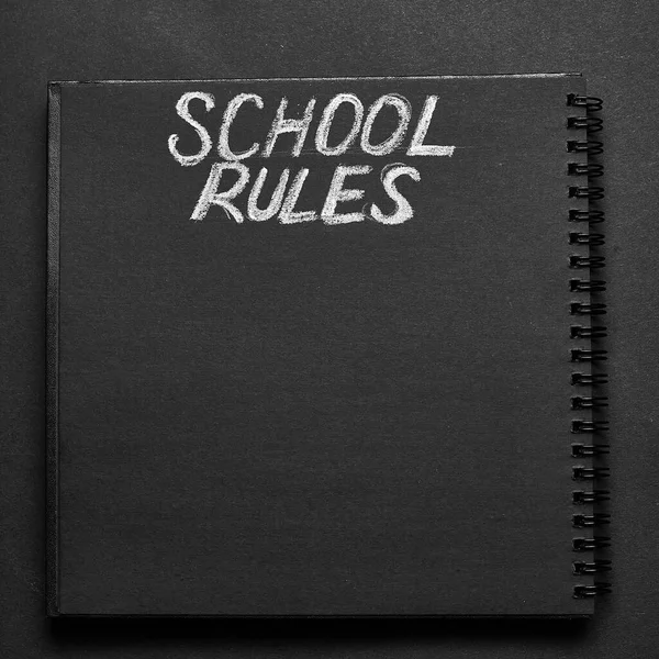 School rules word written on a notepad with blank space. Blank black notepad background.
