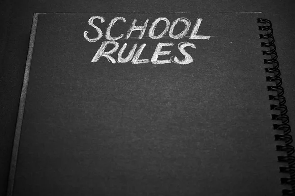 School rules word written on a notepad with blank space. Blank black notepad background.
