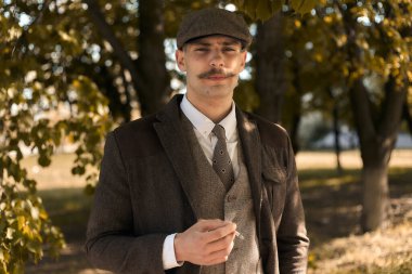 1920 'lerden kalma düz şapkalı bir İngiliz gangsterin portresi. Sokakta sigara içiyor..