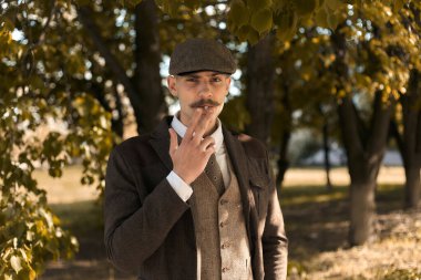 1920 'lerden kalma düz şapkalı bir İngiliz gangsterin portresi. Sokakta sigara içiyor..