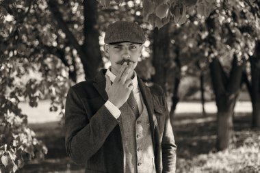 1920 'lerden kalma düz şapkalı bir İngiliz gangsterin portresi. Sokakta sigara içiyor...