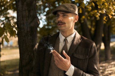 1920 'lerden kalma düz şapkalı bir İngiliz gangsterin portresi. Sokakta sigara içiyor...