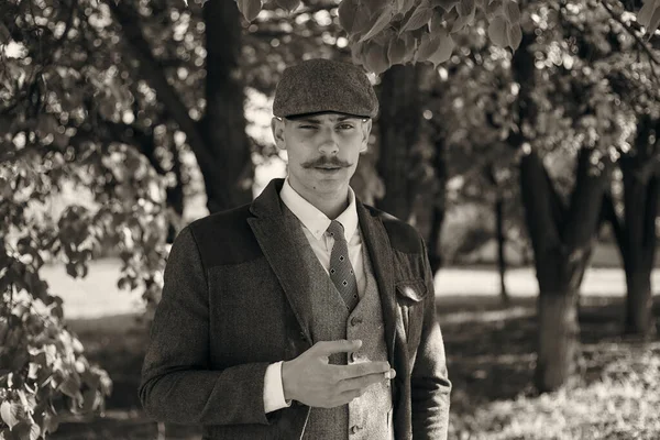 1920 'lerden kalma düz şapkalı bir İngiliz gangsterin portresi. Sokakta sigara içiyor...