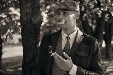 1920 'lerden kalma düz şapkalı bir İngiliz gangsterin portresi. Sokakta sigara içiyor...