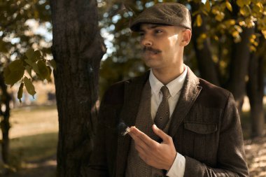 1920 'lerden kalma düz şapkalı bir İngiliz gangsterin portresi. Sokakta sigara içiyor...