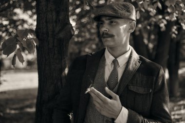 1920 'lerden kalma düz şapkalı bir İngiliz gangsterin portresi. Sokakta sigara içiyor...