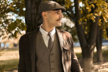 1920 'lerden kalma düz şapkalı bir İngiliz gangsterin portresi. Sokakta sigara içiyor...