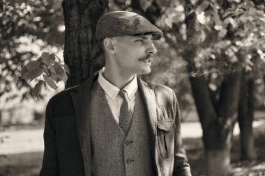 1920 'lerden kalma düz şapkalı bir İngiliz gangsterin portresi. Sokakta sigara içiyor...
